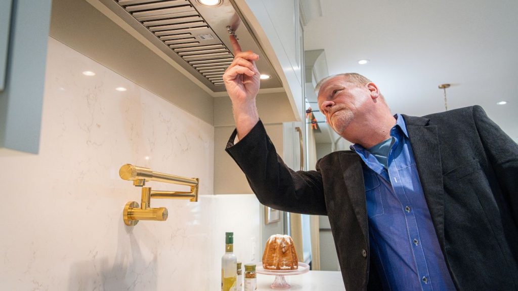 Mike Holmes inspecting the exhaust fan installed.