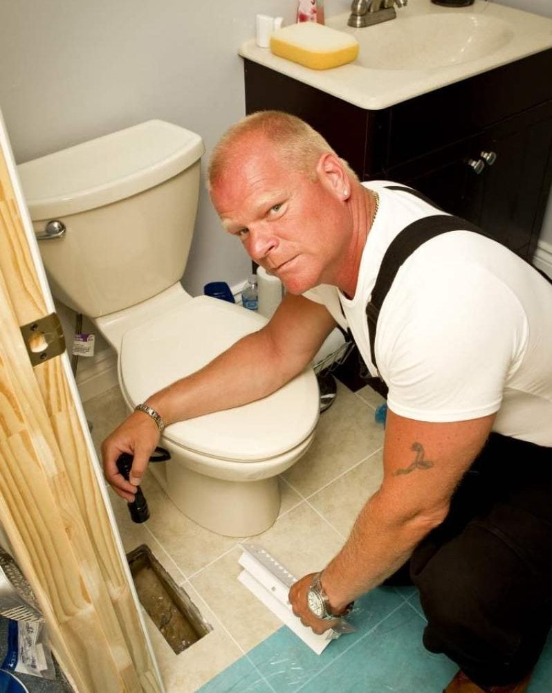 Mike Holmes looking at the toilet in the bathroom - bathroom renovation and construction