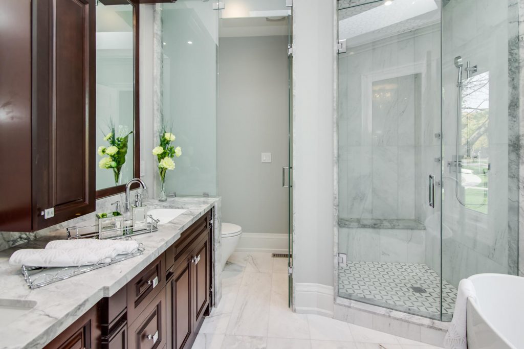 Frosted glass panel and door hides the toilet and provides privacy in this bathroom by Kitchen and Bath at Improve Canada.