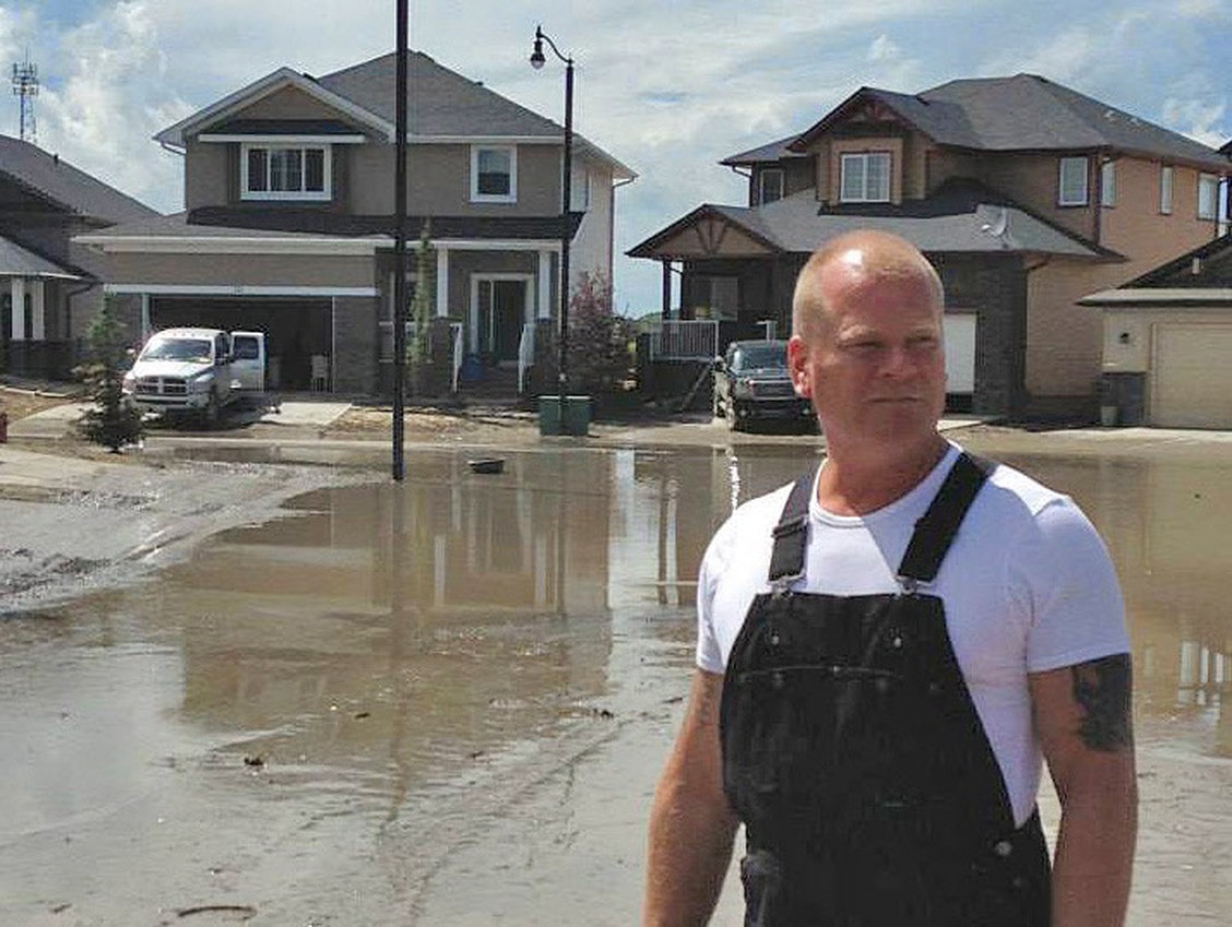 Mike Holmes standing in flooded water