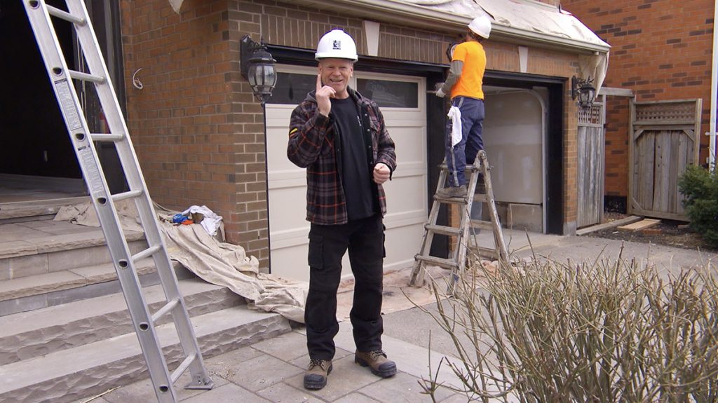 Mike Holmes standing in front of home exterior with brick staining being done.