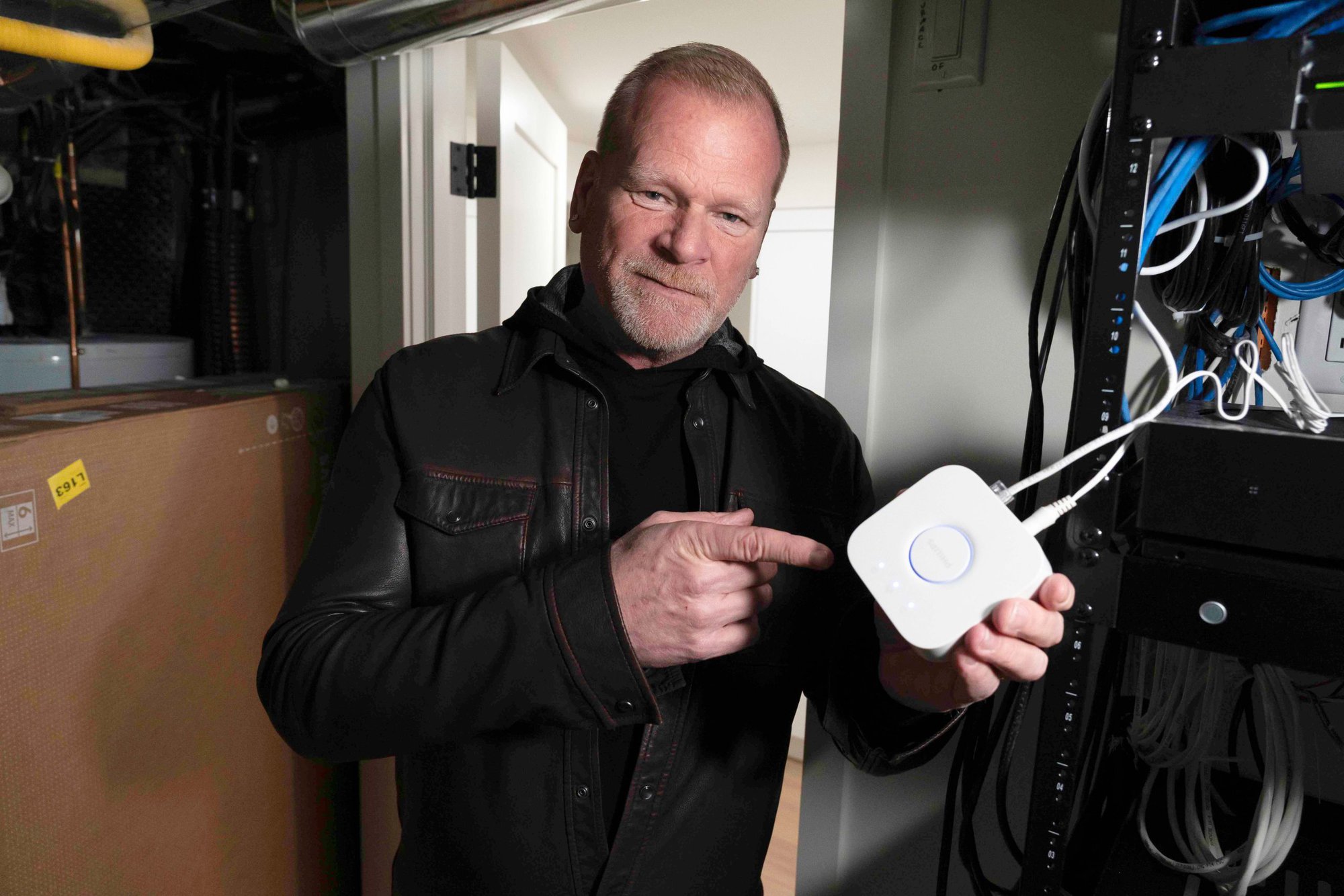 Mike Holmes holding Philips Hue Bridge. Philips Hue Bridge allows you to remotely access and control all your lights from a central location.