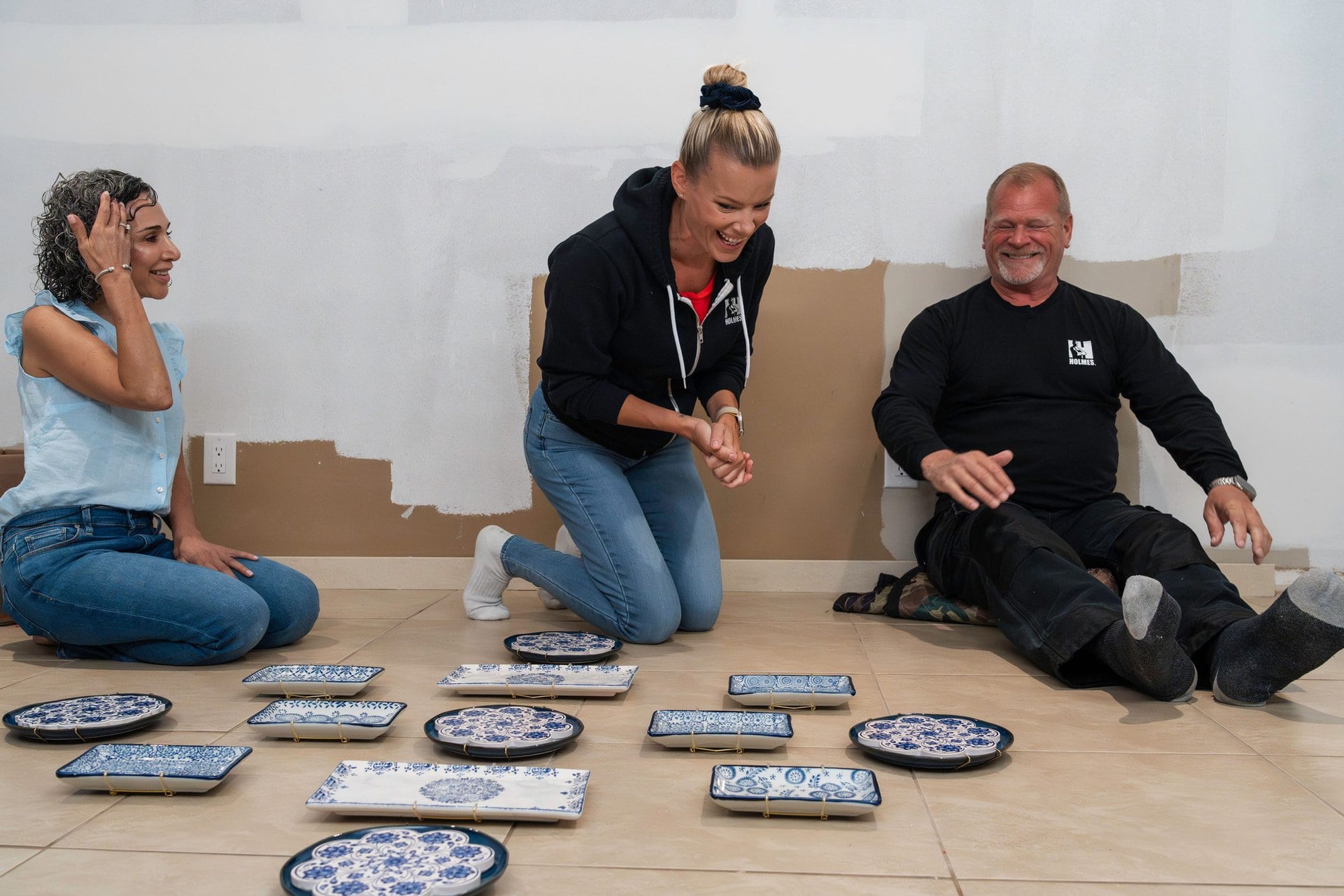Sherry Holmes and Mike Holmes working with Kimmberly Capone to create a personal wall art piece for this homeowner on Holmes Family Rescue Season 2.
