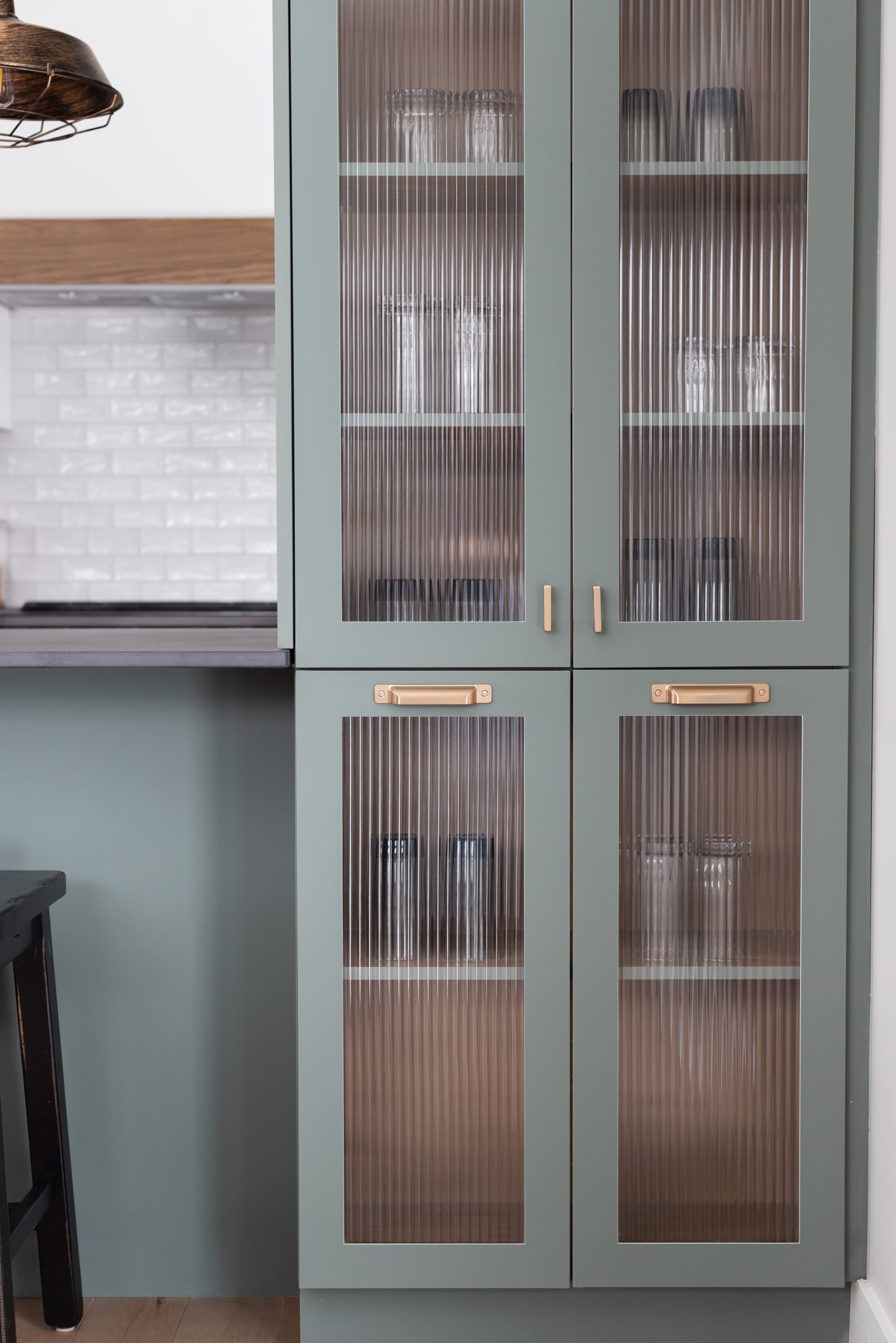 Custom kitchen cabinetry wall unit tailored to fit perfectly, featuring a combination of glass and panel doors, drawers, and adjustable shelves. Designed to maximize storage and showcase personal style while fitting the kitchen’s unique layout.